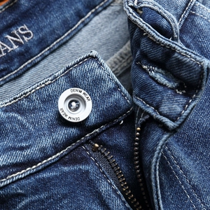 Close-up of blue distressed denim shorts featuring vintage button and contrast stitching