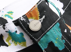 Macro shot of waist button and colorful paint splash pattern on slim fit black jeans