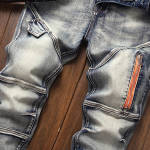 Detail of slim fit denim pants showing distressed wash and orange zipper pocket
