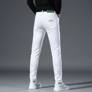 Detail of white slim fit jeans featuring gold CNC embroidery and green leather waist tag