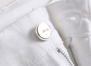 Gros plan de la taille d'un jean blanc avec bouton en métal argenté et tissu texturé
