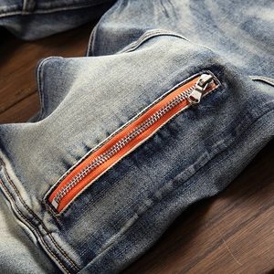 Detail of blue washed denim jeans showing a trendy orange-trimmed zipper pocket