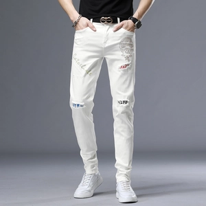 Détail d'un jean blanc ajusté avec déchirures et imprimé tête de mort strass