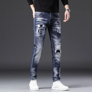Gros plan d'un jean homme ajusté bleu foncé avec des patchs déchirés et des taches de peinture