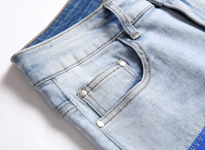 Close-up of light blue jeans pocket with rivet detail and orange contrast stitching