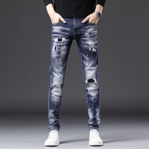 Détail du jean slim pour homme avec effets usés, taches de peinture et empiècements denim
