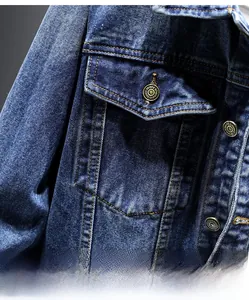 Close-up of deep blue denim jacket showing flap chest pocket and bronze metal button
