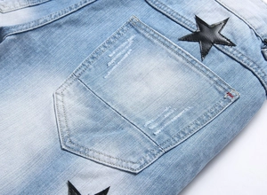 Detail of light blue denim shorts with a black star leather patch on the back pocket