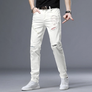 Détails du jean slim blanc avec décor de crâne en strass et patchs déchirés imprimés