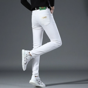 Detail of golden CNC letter embroidery on the back pocket of slim fit white denim jeans