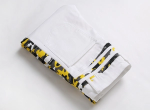 Détail du jean camouflage blanc avec des motifs contrastés jaune et gris sur le côté
