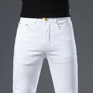 Detail of slim fit white denim jeans with gold button and rivet on the waistband