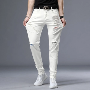 Détail d'un jean slim blanc avec des trous usés et un imprimé tête de mort en strass