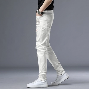 Gros plan détaillé du jean slim blanc pour homme avec trous usés et motif de crâne brillant