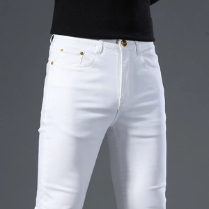 Close-up of white slim fit jeans featuring gold embossed buttons and metal rivets details