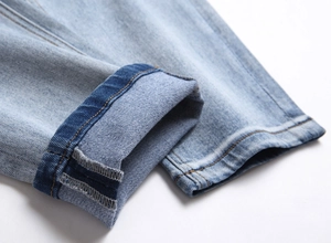 Close-up of light blue denim jeans cuff showing dual stitching and cuffed hem detail