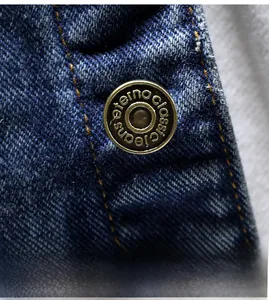 Macro shot of vintage bronze button on high-density dark blue denim jacket fabric