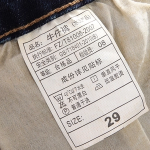 Detailed close-up of the white wash care label with size 29 on dark blue denim jeans