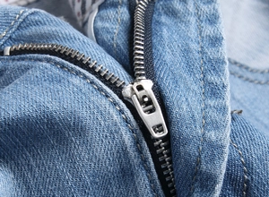 Macro shot of durable metal zipper and denim fabric texture on blue denim shorts