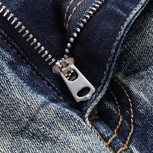 Detail of high-quality silver metal zipper on slim-fit blue washed denim jeans