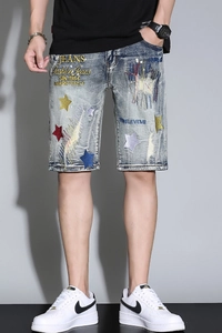 Detailed close-up of colorful star embroidery on men's vintage blue denim shorts