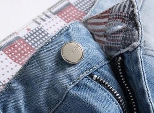 Macro view of blue denim jeans waist with silver button and star pattern lining