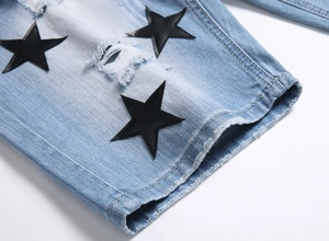 Detailed macro view of black star leather patches and distressed denim texture on shorts