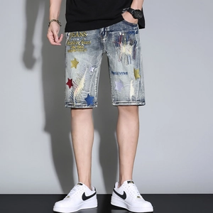 Detail view of men's blue denim shorts featuring colorful star embroidery and vintage wash