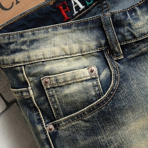 Close-up of vintage wash denim shorts featuring yellow distressed finish and metal rivets