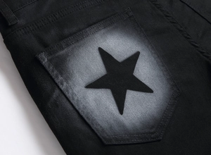 Detail of black denim back pocket featuring grey spray paint and a star motif