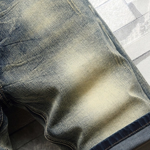 Close-up of vintage blue denim shorts showing heavy yellow wash texture and contrast stitching