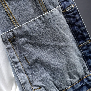 Close-up of blue patchwork denim jacket with yellow stitching and contrast pocket detail