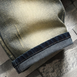 Detail shot of vintage washed denim fabric with roll-up hem and contrast stitching
