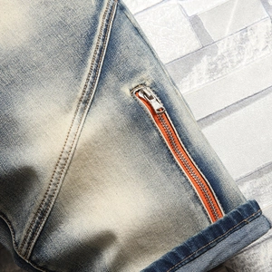Détail du jean délavé bleu clair avec doublure orange et fermeture éclair en métal
