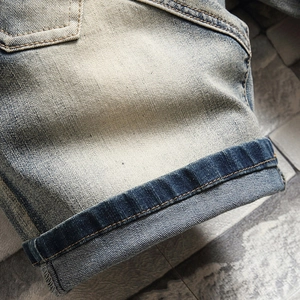 Détail du short en jean délavé clair avec ourlets retroussés et effet usé blanc