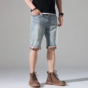 Detail of light blue denim shorts featuring distressed holes and geometric pattern cuffs