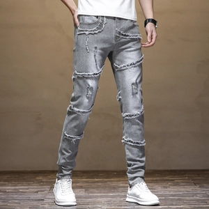 Detail of light gray slim fit biker jeans with frayed seams and distressed denim texture