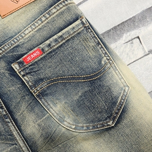 Detail of light blue vintage wash denim shorts with back pocket and red brand label
