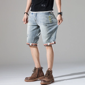 Men's light blue distressed denim shorts with yellow embroidery and patterned cuffs