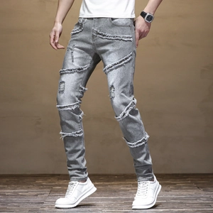 Detail of light gray slim fit jeans featuring stylish horizontal distressing and frayed edges