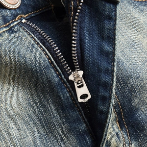 Gros plan du rabat en denim avec fermeture éclair métallique et coutures contrastées