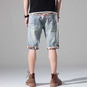 Detail of light blue denim shorts with colorful woven patterns and mountain embroidery