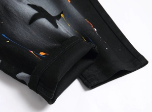 Detail of street style black denim jeans with colorful paint splatter and star pattern