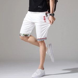 Dettaglio degli shorts in denim bianco con ricami etnici su tasche e orli risvoltati