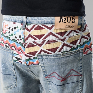 Detail of light blue denim shorts with colorful ethnic weaving and leather logo patch