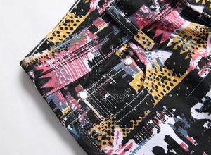 Detail of colorful graffiti print jeans with reinforced metal studs and belt loops