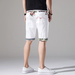Vista dettagliata degli shorts in denim bianco da uomo con patchwork etnico e ricamo rosso