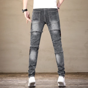 Détail de la poche arrière du jean avec patchwork coloré et coutures effilochées tendance