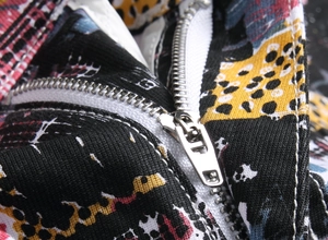 Macro view of a durable silver metal zipper on colorful geometric print stretch denim pants
