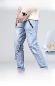 Détail de ce jean bleu clair vieilli avec œillets métalliques et finitions zippées